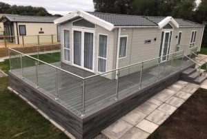 Grey Trex decking around holiday home with clear glass railing