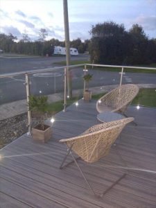 Grey Trex deck with glass railings and spotlights