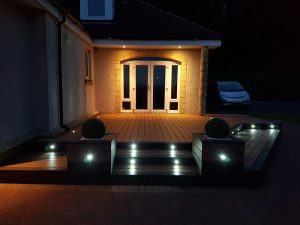 Raised deck area with spotlights and planters at night